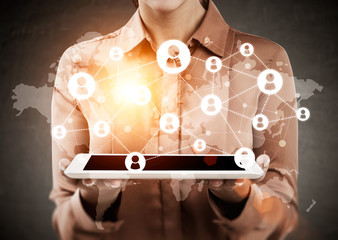 Woman in brown shirt is holding tablet with world map and networ