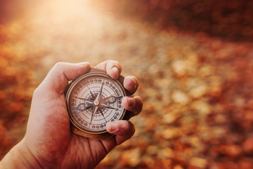 Hand holding a compass on natural blurry background