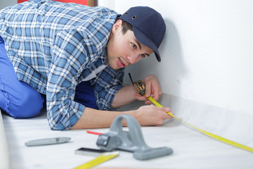 handyman measuring unfinished room in new house