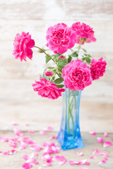 Obraz na płótnie Canvas Still life with pink roses flower in blue vase on grunge wooden