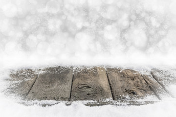 Alte Holzbretter im Schnee mit Bokehhintergrund