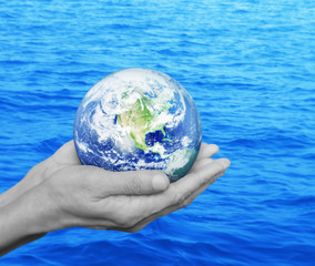 Earth in black and white hands over blue sea background, Environ