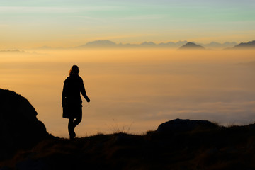 Silhouette of a hiker in the mountains with the sea of fog in th