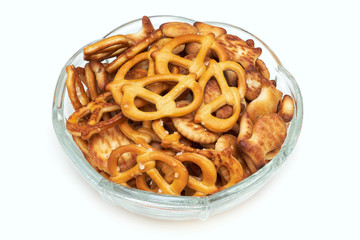Mix of salty snacks (crackers and pretzels) in glass bowl isolated on white background