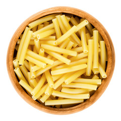Macaroni pasta in wooden bowl, Italian maccheroni, short-cut noodles in the shape of narrow tubes. Uncooked dried durum wheat semolina pasta. Isolated macro food photo over white background. 