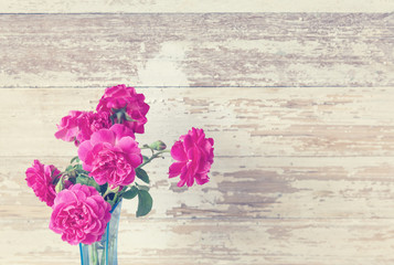 Still life with pink roses flower in blue vase on grunge wooden