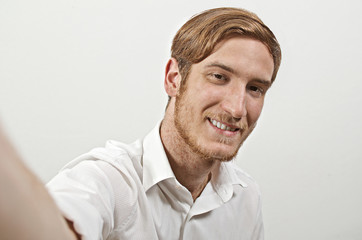 Obraz premium Young Smiling Adult Man in White Shirt Takes a Selfie