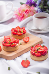 Вкусные десерты с клубникой на столе на светлом фоне