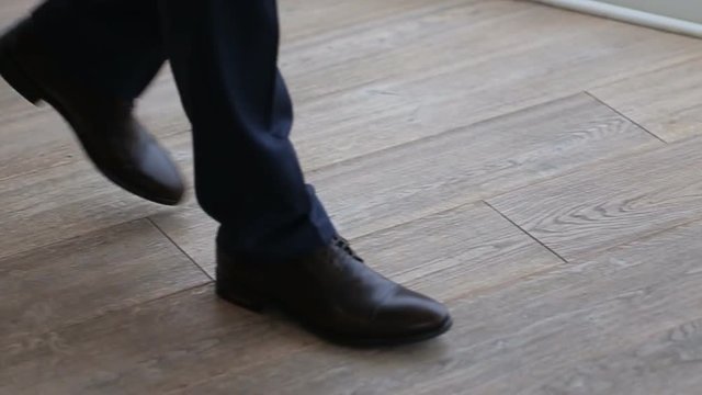 Close up of businessmen legs in black shoes and trousers walking on the floor