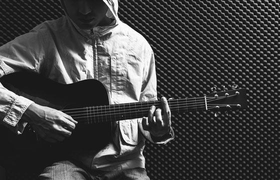 BW asian guitarist playing acoustic guitar in recording studio