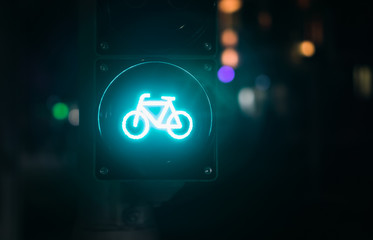 Eine grün leuchtende Ampel für Radfahrer bei Nacht mit Linsenreflexen im Hintergrund