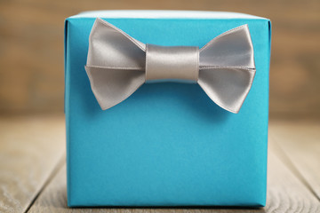 light blue gift box with minimalistic silver ribbon bow on wooden