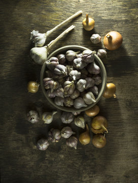 Heads of garlic in bowl on the old wooden background.