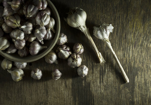 Heads of garlic in bowl on the old wooden background.