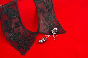 Black lace collar and earrings on red background