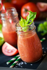 Fresh tomato and celery detox smoothie in a glass jar on a black slate board