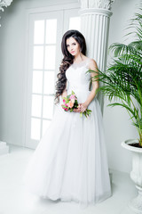 gorgeous bride in luxury wedding dress. Bride. Perfect Make up and Long Wavy Hair. Hairstyle, wedding  jewelry. Beautiful Woman with Shiny Brown Hair. gorgeous wedding bouquet of various flowers.