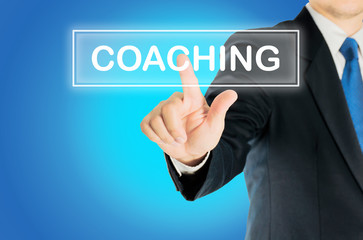 Business man is pushing COACHING transparent button word over blue gradient background, business...