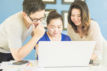 Two women and one man are happily looking at computer in modern office