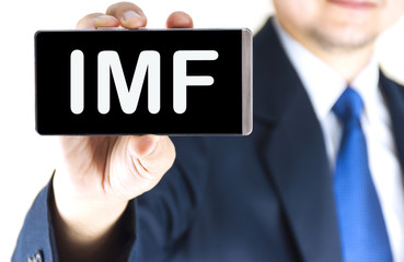 IMF word on mobile phone screen in blurred young businessman hand over white background, business concept
