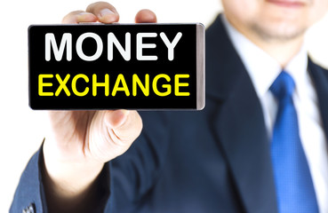 MONEY EXCHANGE word on mobile phone screen in blurred young businessman hand over white background, business concept