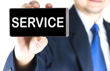 SERVICE word on mobile phone screen in blurred young businessman hand over white background, business concept