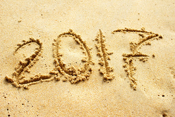 2017, message written in the sand at the beach background
