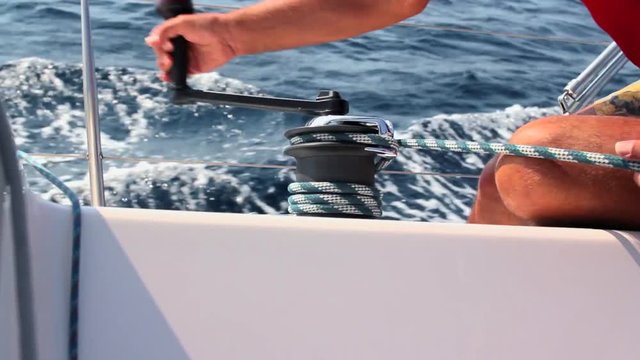 Sailing, man pulling rope, winding rope around winch