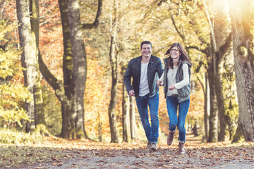 Junges Paar läuft freudestrahlend durch den Herbstwald