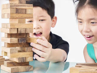 Children are playing jenga, a wood blocks tower game for practicing their physical and mental skill