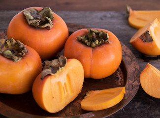 Kaki Früchte auf Kupferteller