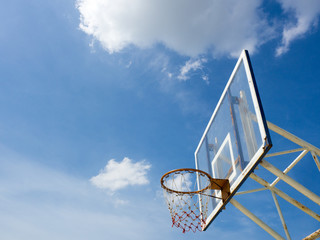 Old basketball hoop with backboard against  blue sky, white cloud