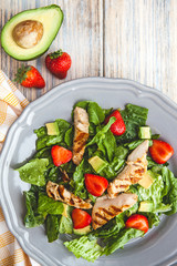 fresh salad with greens, avocado and strawberry, top view