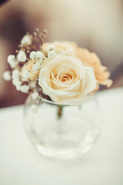 Single flower of white rose in round glass vase on the table. Floral decor elements. Concept for romantic greeting card  birthday, valentine, mothers day or weeding