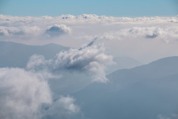 View over the clouds in the sky with mountains in the background