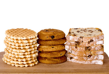 Piles of wafers, oatmeal biscuits and cake on wooden board, isol