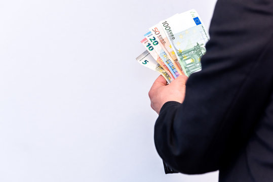 Male in suit holds Euro banknotes in cash in his hands