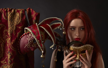 Beautiful redheaded woman with carnival masks on black backgroun