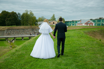 Fototapeta premium Happy bride and groom walking from back