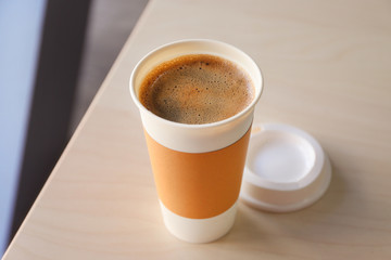 Coffee-to-go. Opened paper cup of coffee on table
