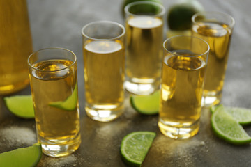 Gold tequila shots with lime and salt on gray table