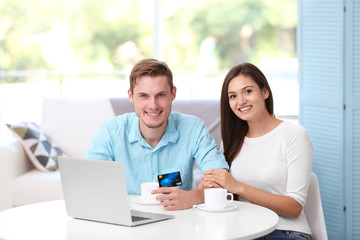Obraz premium Happy couple sitting at table and making online shopping