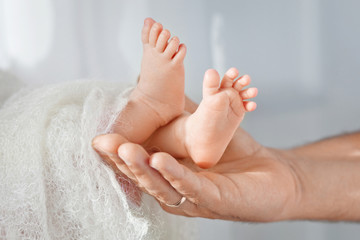 Baby feet in father hands. Tiny Newborn Baby's feet on male shap