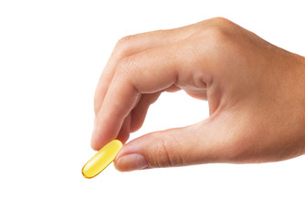 Fish oil pill in female hand on light background