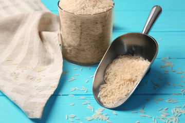 Metallic scoop with rice on wooden background