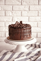 Tasty chocolate cake on brick wall background