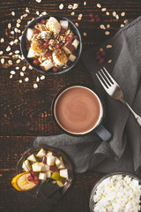 Oatmeal with apple, banana, berries and coffee on a wooden table