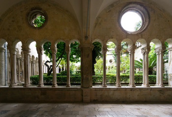 The architectural archways, columns and windows that look on the formal garden of the Franciscan Monastery of Dubrovnik in Croatia.