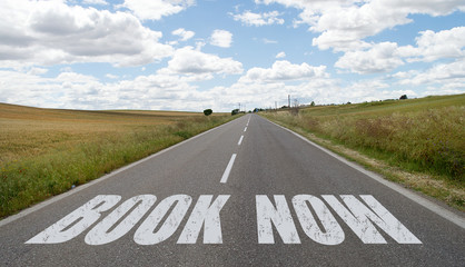 Book now message written on the road