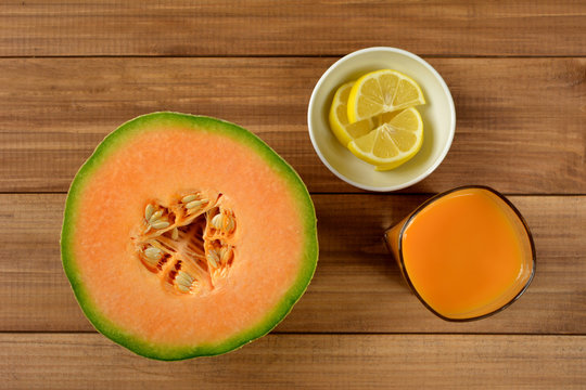 Cantaloupe melon fruit, lemon and juice on wooden background. Top view.